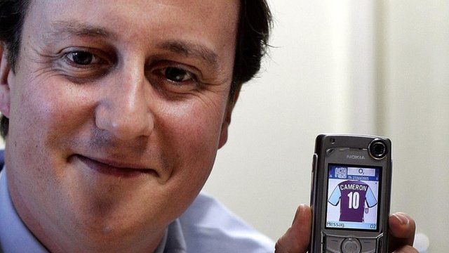 Mr Cameron, pictured in 2005, holding a phone with an image of an Aston Villa shirt with this name on it