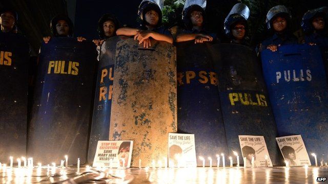 Anti-riot policemen with their shields stand next to lit candles