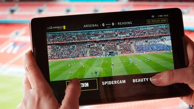 Fan holds up a tablet with a new app on it using 4G Broadcast to provide instant replays of the action