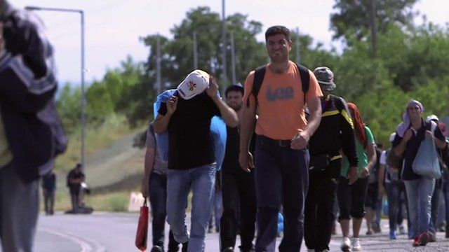 Long line of migrants walking along a road in Europe