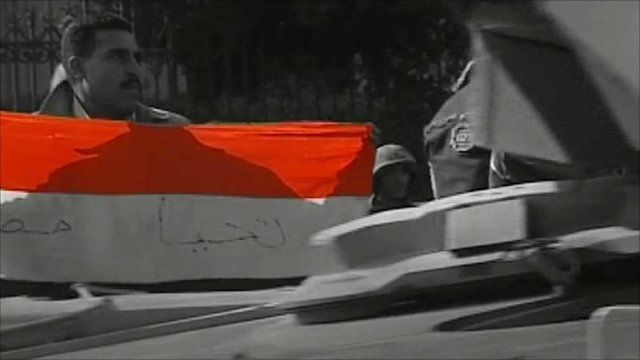Protester with flag and passing tank