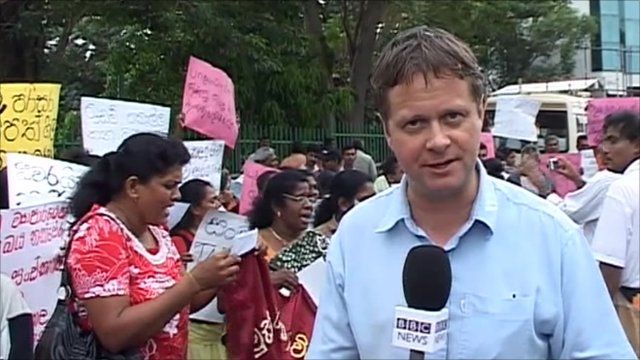 The BBC's Charles Haviland in front of protestors holding banners in western Sri Lanka