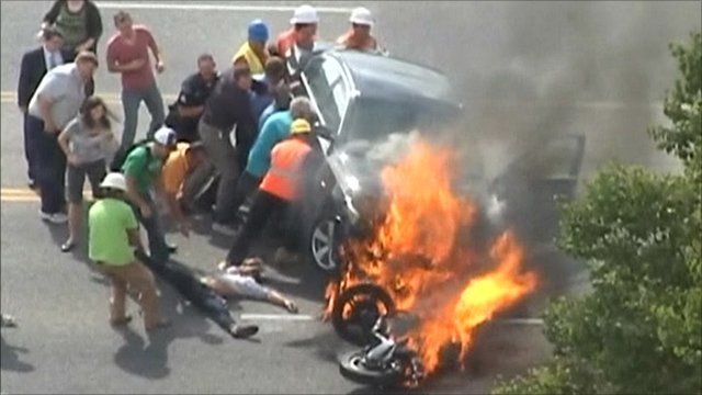 Passers-by lifting the car as the victim is pulled to safety