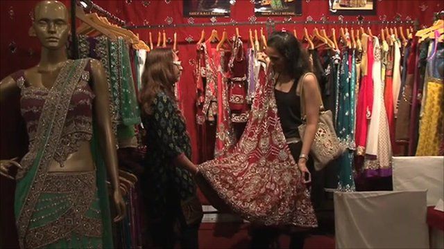 An Indian woman holds a potential wedding dress against her
