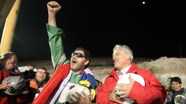 Luis Urzua (L) is greeted by President Sebastian Pinera