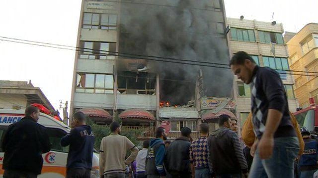 Crowd watching smoke pouring from building