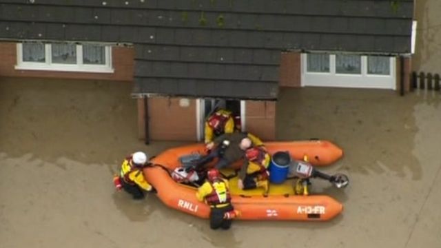 Rescue boat helping someone from their flooded house