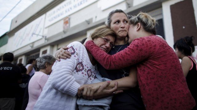 People embrace outside a club where the Red Cross set up a centre to help flood victims in La Plata