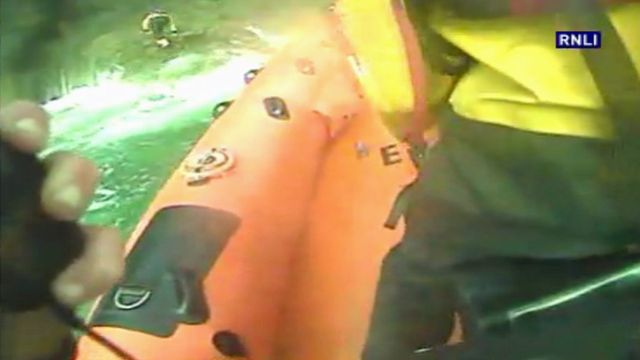 RNLI crew member scrambles on to rocks