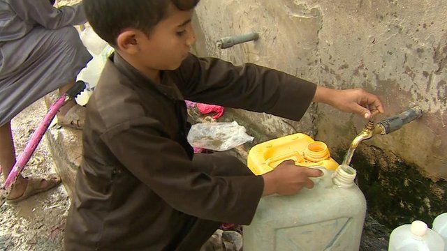 Young boy filling container with water