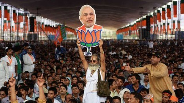 A supporter of the Bharatiya Janata Party holds an image of Narendra Modi.