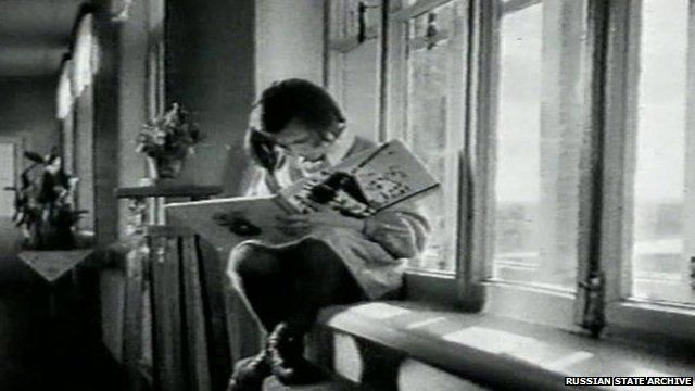 Child sitting on a windowsill, reading a book