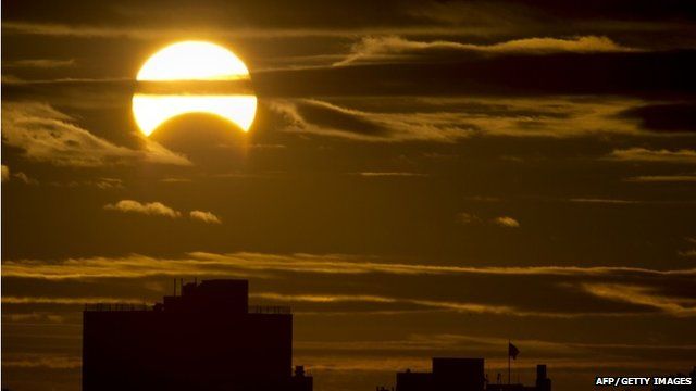 A partial Solar eclipse is seen just after sunrise over the Queens borough of New York across the East River on November 3, 2013