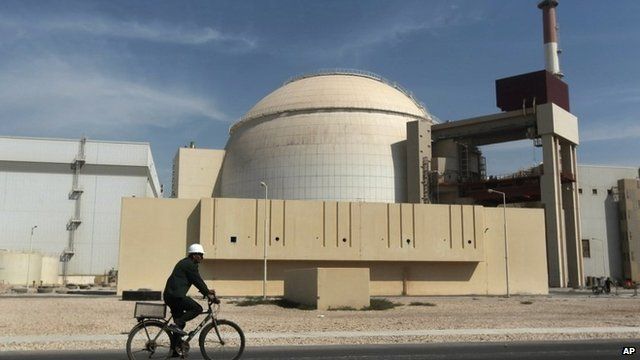 A man rides a bicycle in front of the reactor building of the Bushehr nuclear power plant, Iran