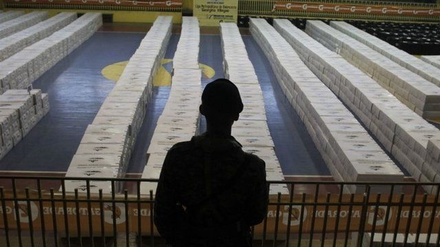 A soldier stands guard near boxes containing electoral papers for distribution at polling stations, at a gym in San Pedro Sula November 21, 2013