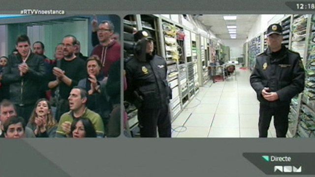 A split-screen shot from RTVV's last broadcast showing workers on one side in a TV studio and police officers waiting to pull the power plug on the other side