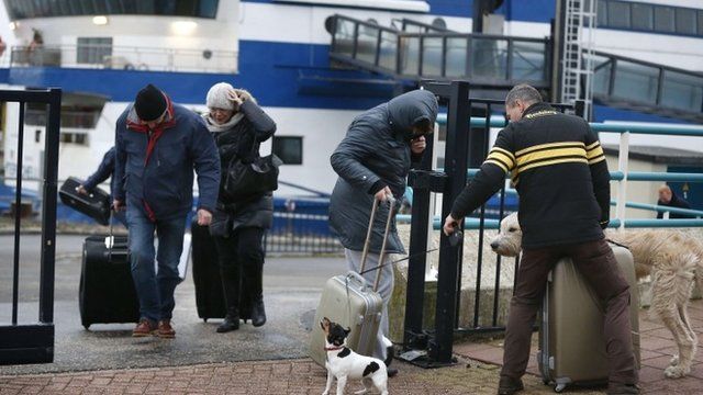 Passengers in the harbour of Harlingen, The Netherlands, struggle with the wind