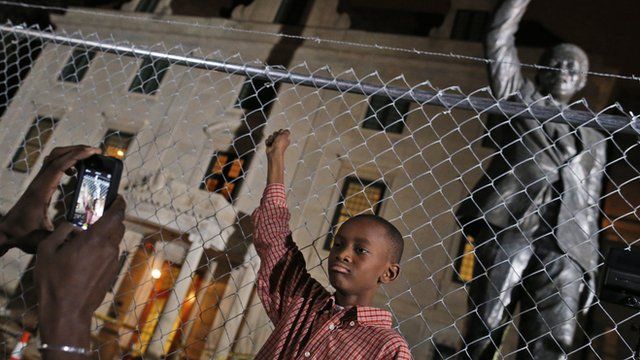 Young boy poses in front of Nelson Mandela statue