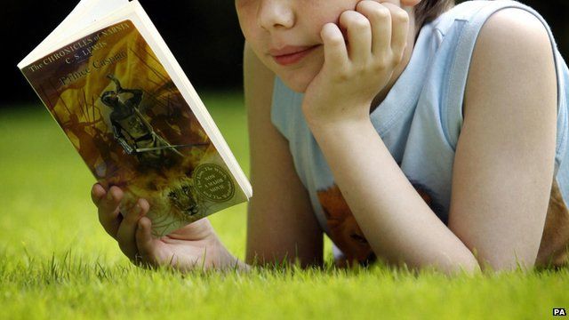 A child reads a book on the grass