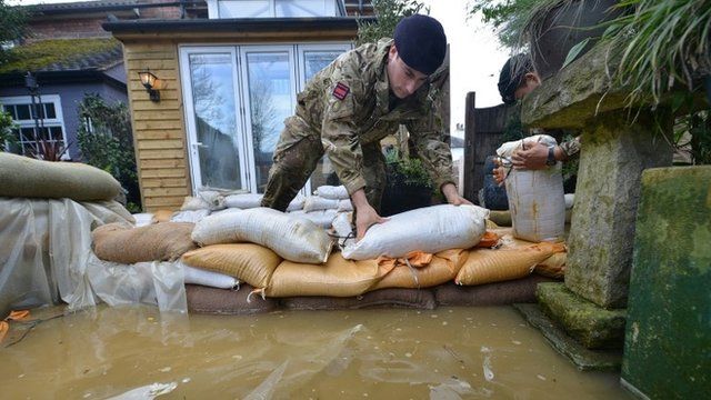 Soldier stacking sandbags outside flooded house
