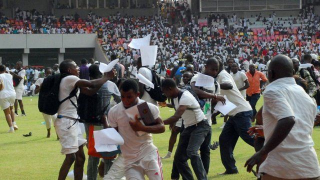 Jobseekers scramble as their exam papers fly in the air, on the pitch of Abuja National Stadium, Nigeria
