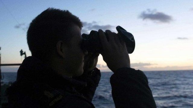 A man searching from aboard an Australian Navy ship