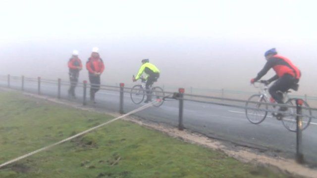 Rescuers walking along a road as cyclists ride past