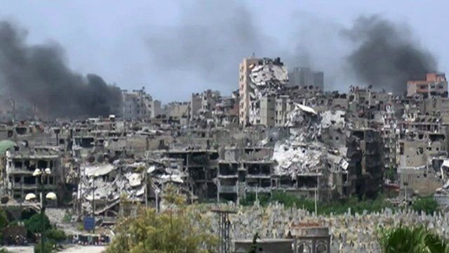 Smoke above destroyed buildings in Homs