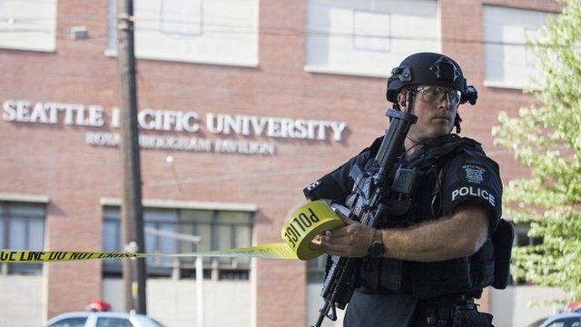 An armed police officer secures the scene of the shooting