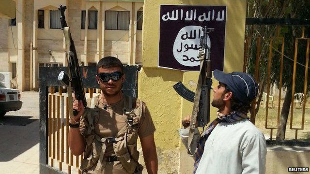 Islamic State militants stand guard after taking control of a government building in the Christian town of Bartella, Nineveh province - 7 August 2014