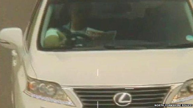 A police still of Roy "Chubby" Brown driving while reading The Sun