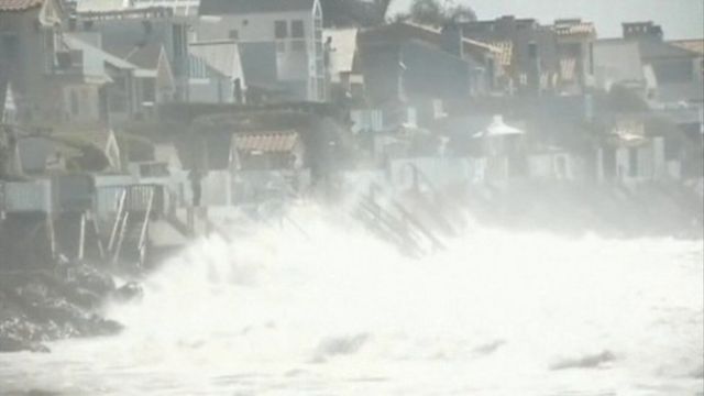 Waves crash against houses