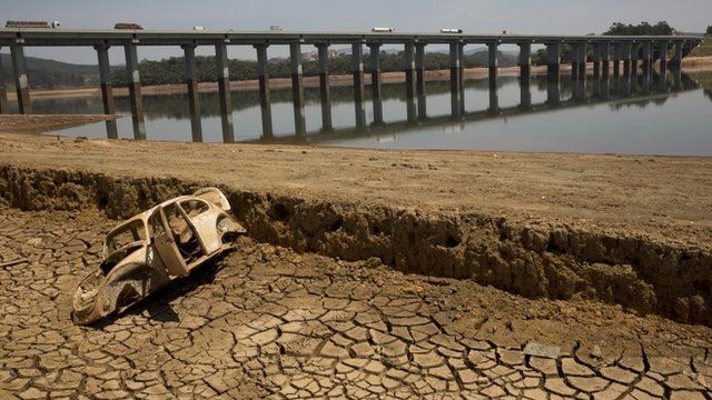 The frame of a car sits on the cracked earth at the bottom of the Atibainha dam