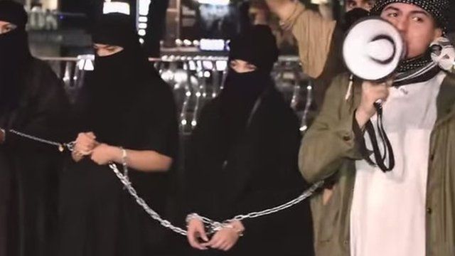 A man holding a megaphone in front of some actors dressed as slaves