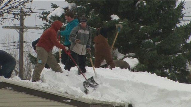 People clearing snow from a roof
