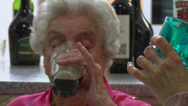 Elderly woman drinks cocktail