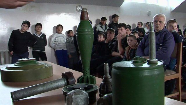 Students in Nagorno-Karabakh looking at ordnance on a table during a lesson on identifying mines and bombs left over from the Armenia-Azerbaijan conflict