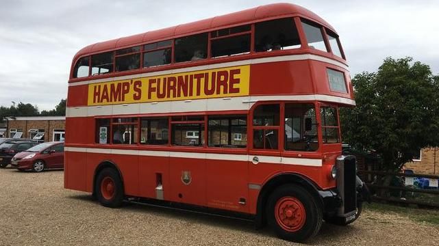 Red double decker bus with "Harris Furniture" advert