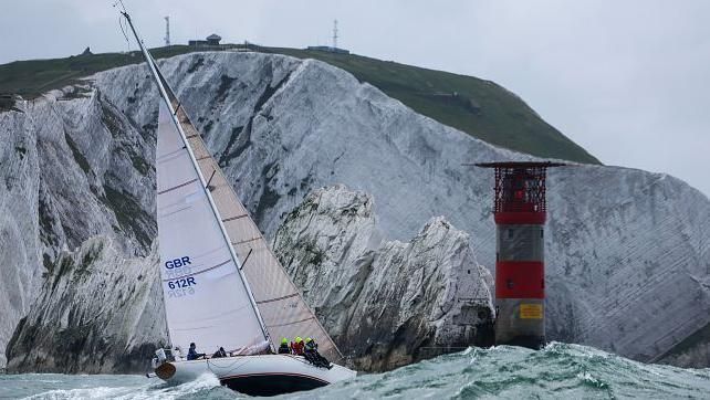 Firebrand yacht with white sails travelling past the Needles on the isle of wight