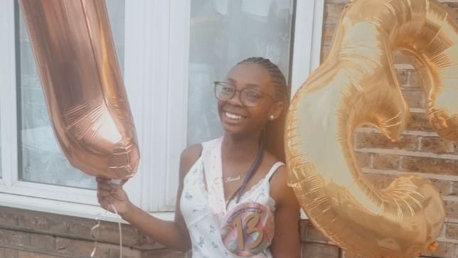 A smiling Hannah Jacobs holding birthday balloons 