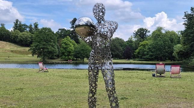 A metal human figure sculpture on grass