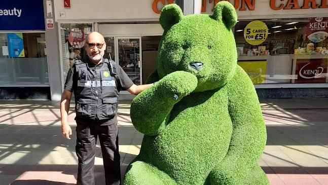 Ahmed Bensharif alongside a giant bear figure covered in artificial grass 