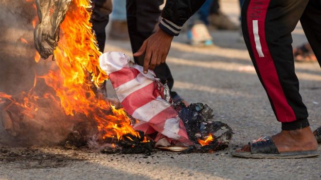 raqis burns the American flag in the southern city of Basra on December 30, 2019
