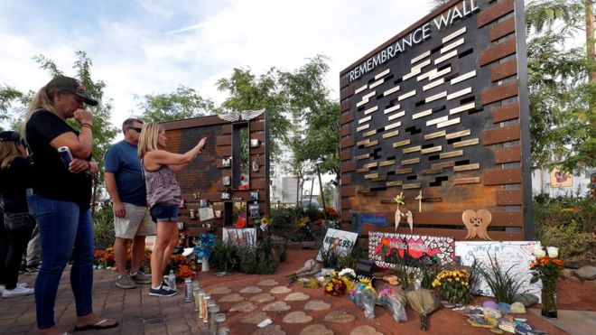 Скорбящие смотрят на Стену памяти жертв стрельбы в Лас-Вегасе, которая до сих пор остается самой смертоносной стрельбой в истории США