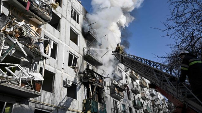 Firefighters work on a fire on a building after bombings on the eastern Ukraine town of Chuguiv on February 24, 2022,