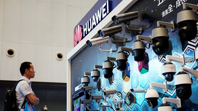 Человек стоит перед экраном камер наблюдения Huawei
