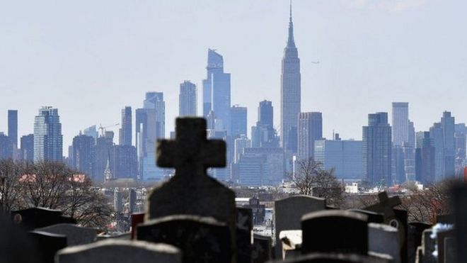 Gravestones from a cemetery are seen with the Manhattan skyline
