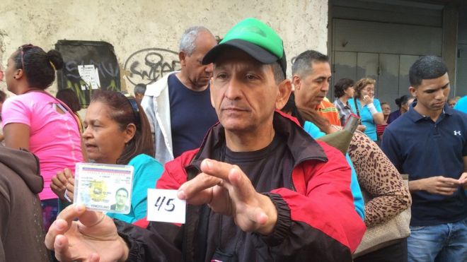 Мужчина несет продовольственные билеты в Каракасе (февраль 2016 года)