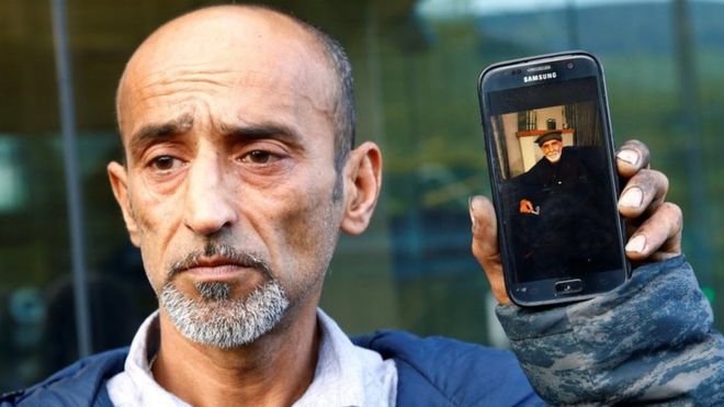 Омар Наби держит телефон с фотографией своего отца Дауда, который погиб в расстреле мечети Крайстчерч (16 марта)