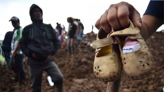 Человек показывает некоторые детские туфли после оползня, в деревне Портачуэло, в муниципалитете Росас, Каука, Колумбия, 22 апреля 2019 года.